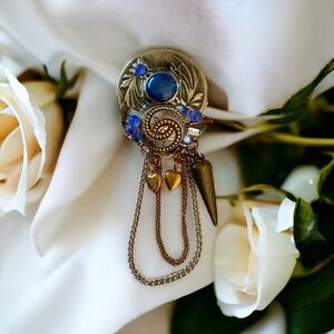 Antique style adorned sterling silver brooch with a blue center cabochon Stone